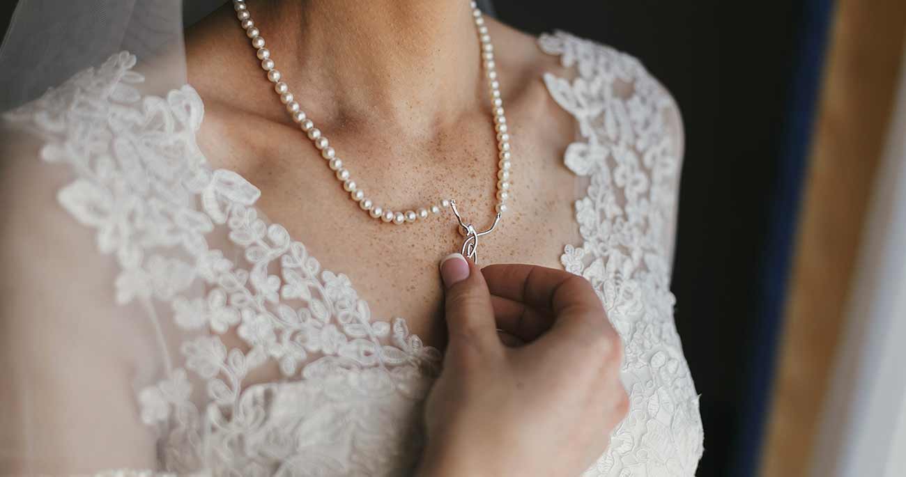 A woman wearing pearls and holding onto a necklace