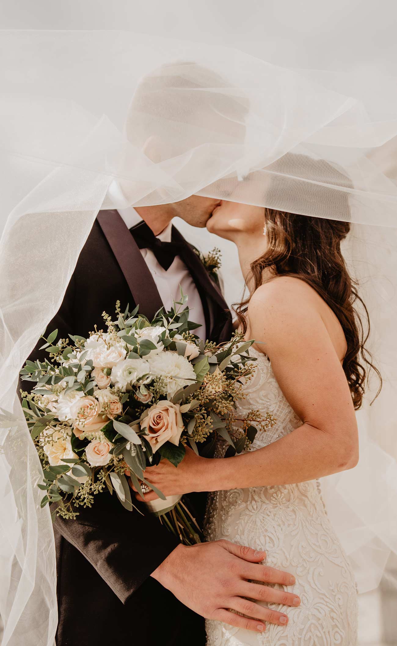 A bride and groom kissing under the veil