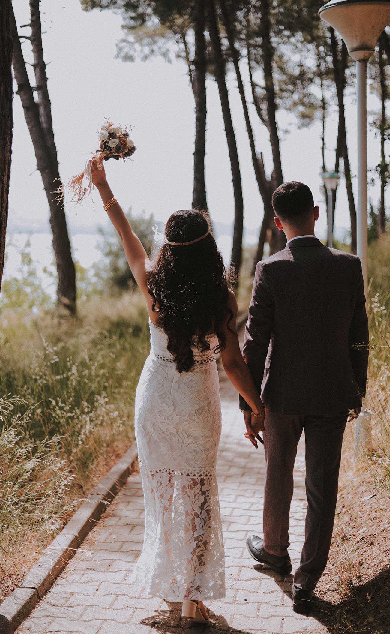 A bride and groom walking down the path of a forest.