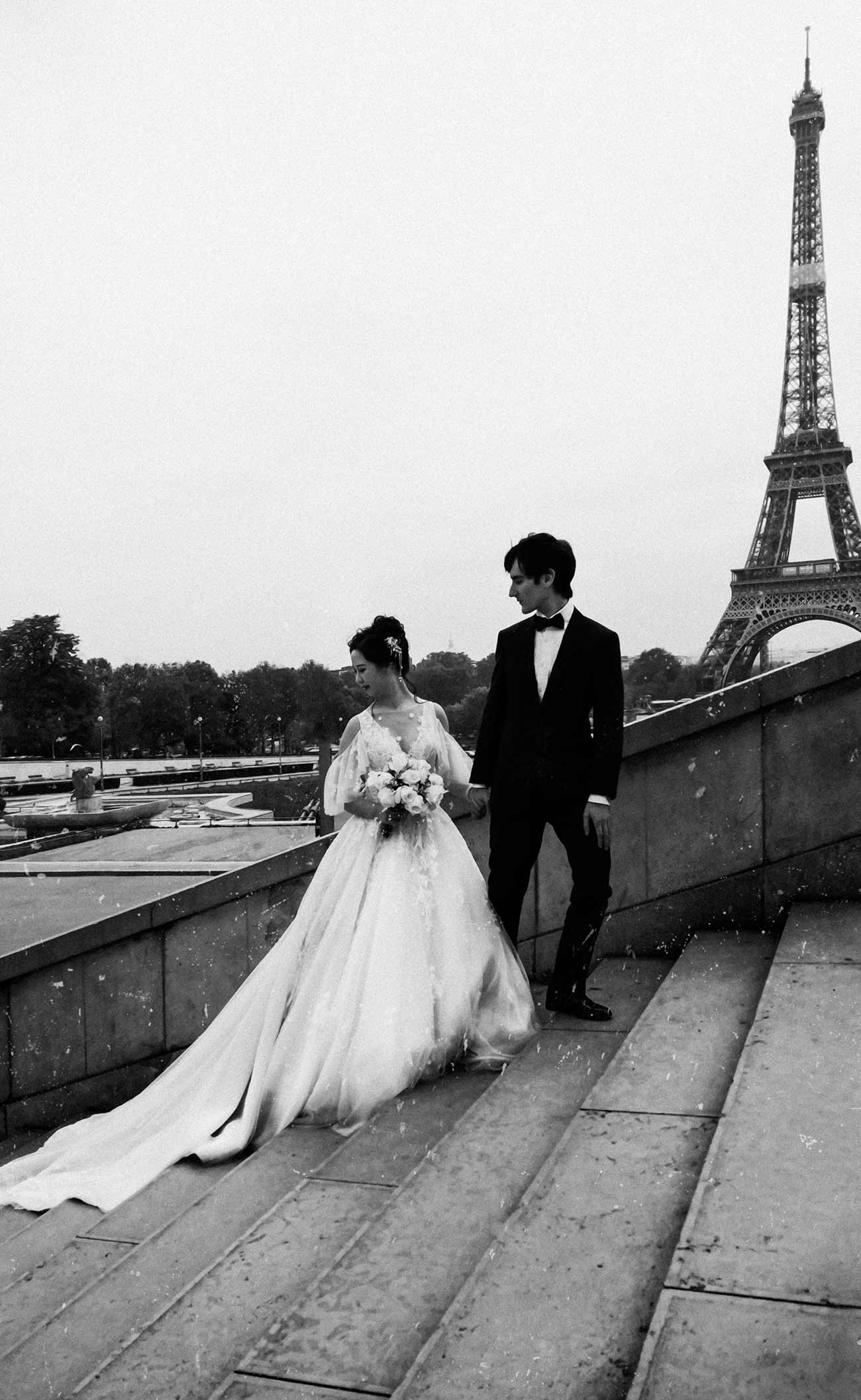 A man and woman standing on steps near the eiffel tower.