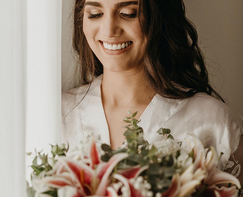 A woman holding flowers in her hands and smiling.