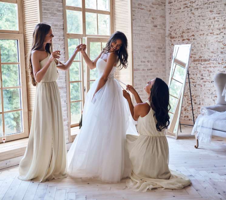 Three women in white dresses are posing for a picture.