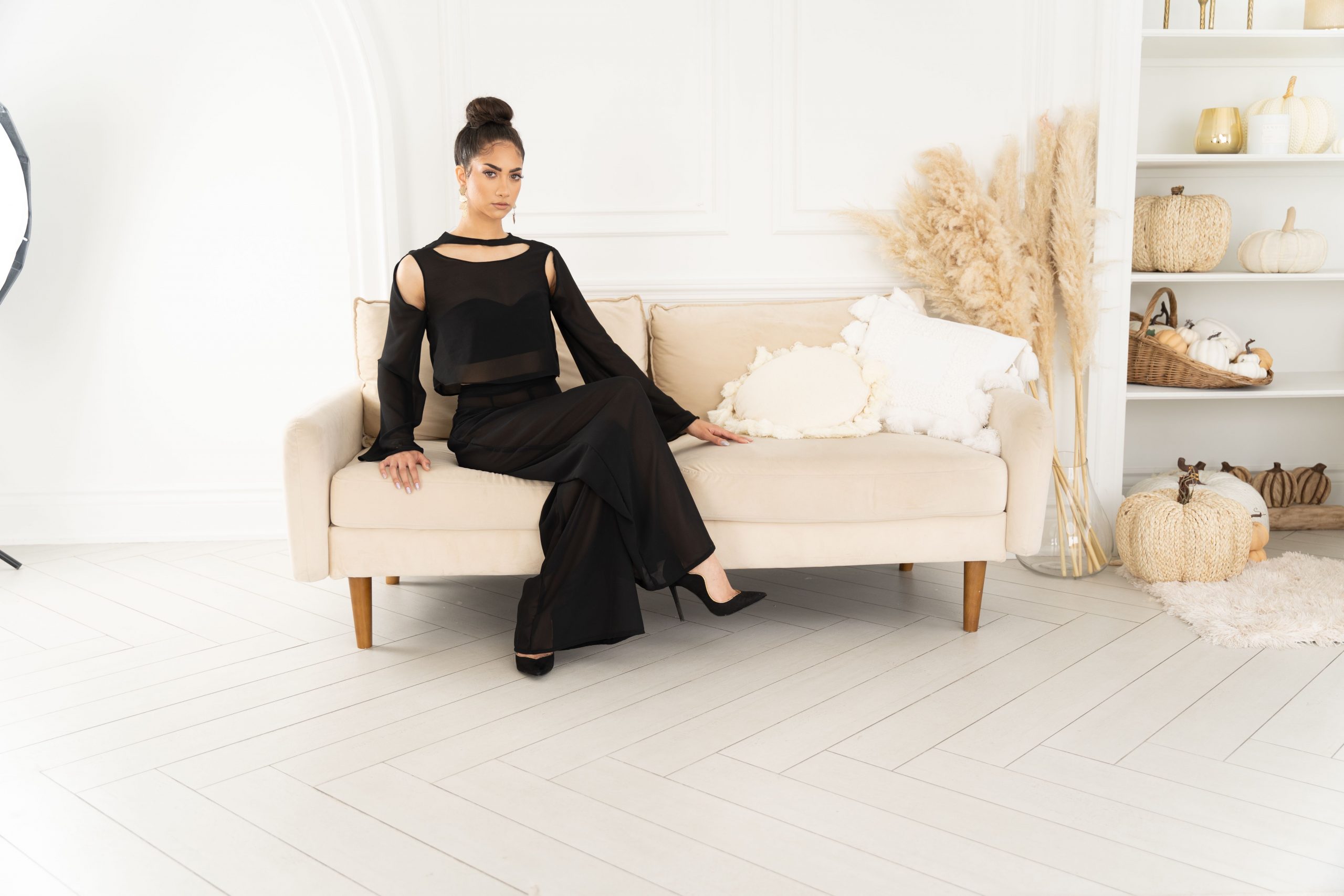 A woman in black dress sitting on a couch.