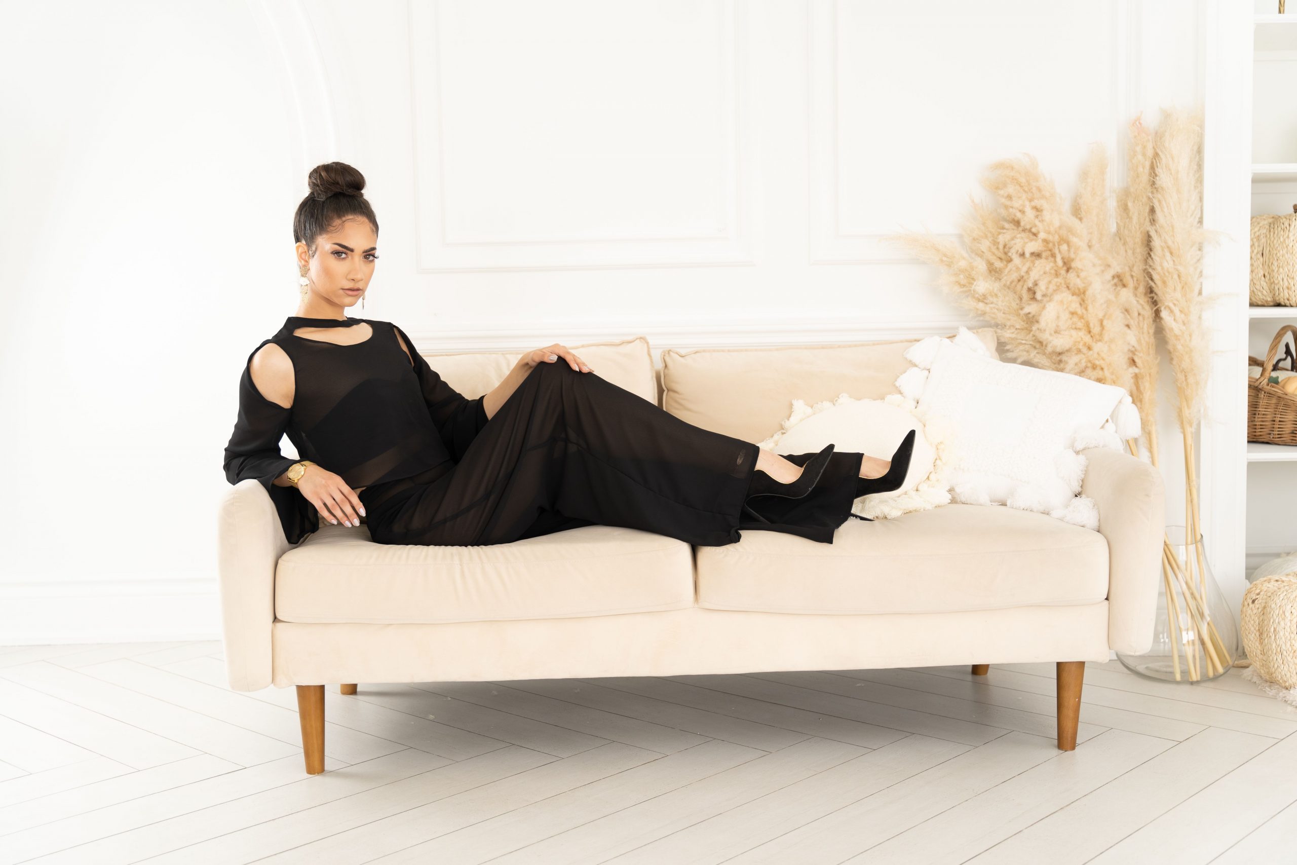 A woman in black dress sitting on top of couch.