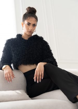 A woman sitting on top of a couch wearing black pants.