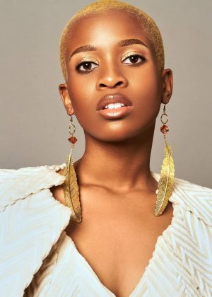A woman with short blonde hair wearing gold earrings.
