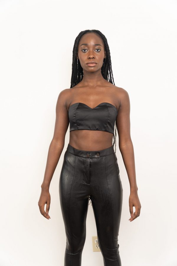 A woman in black leather pants and bra top.