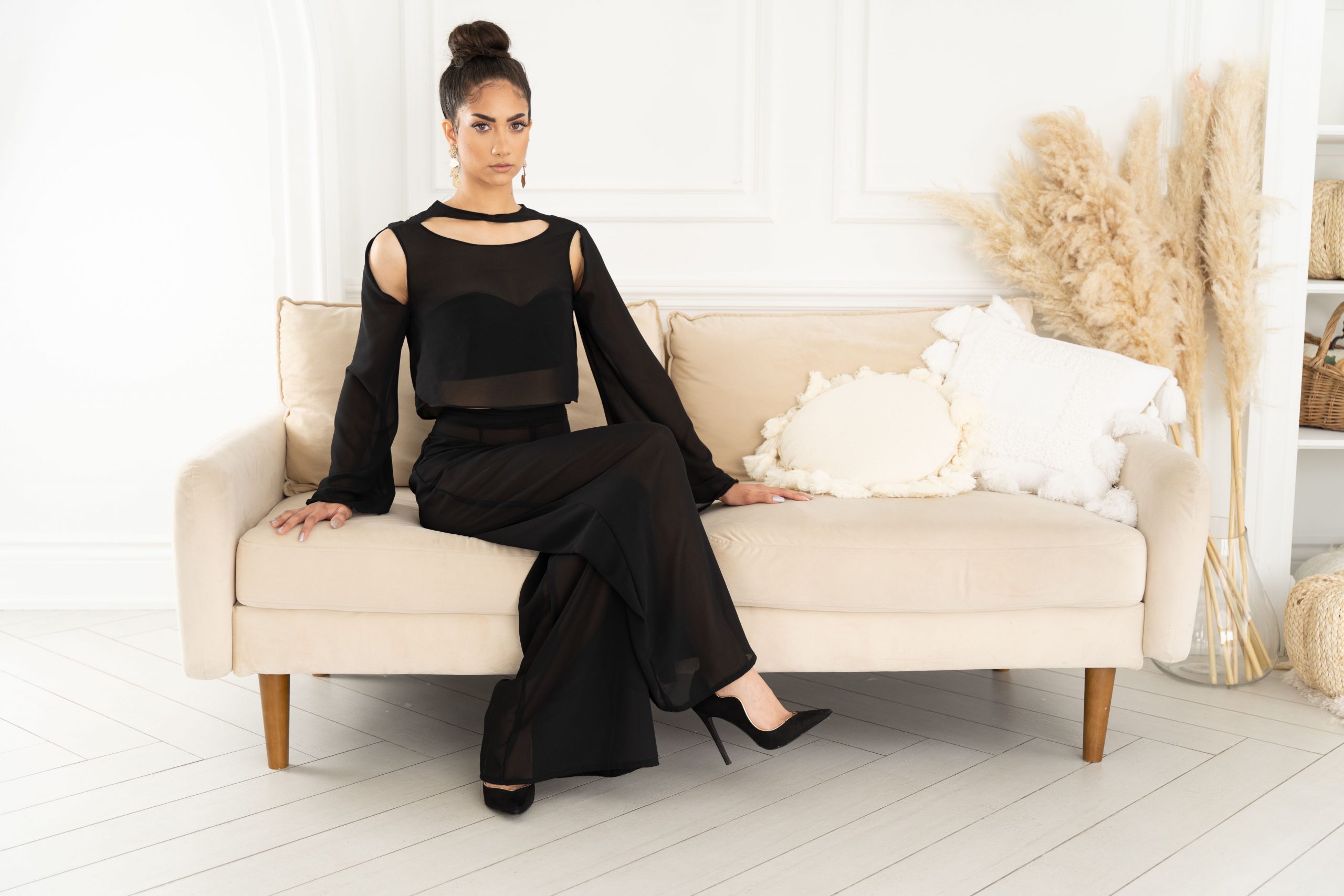 A woman in black dress sitting on couch.