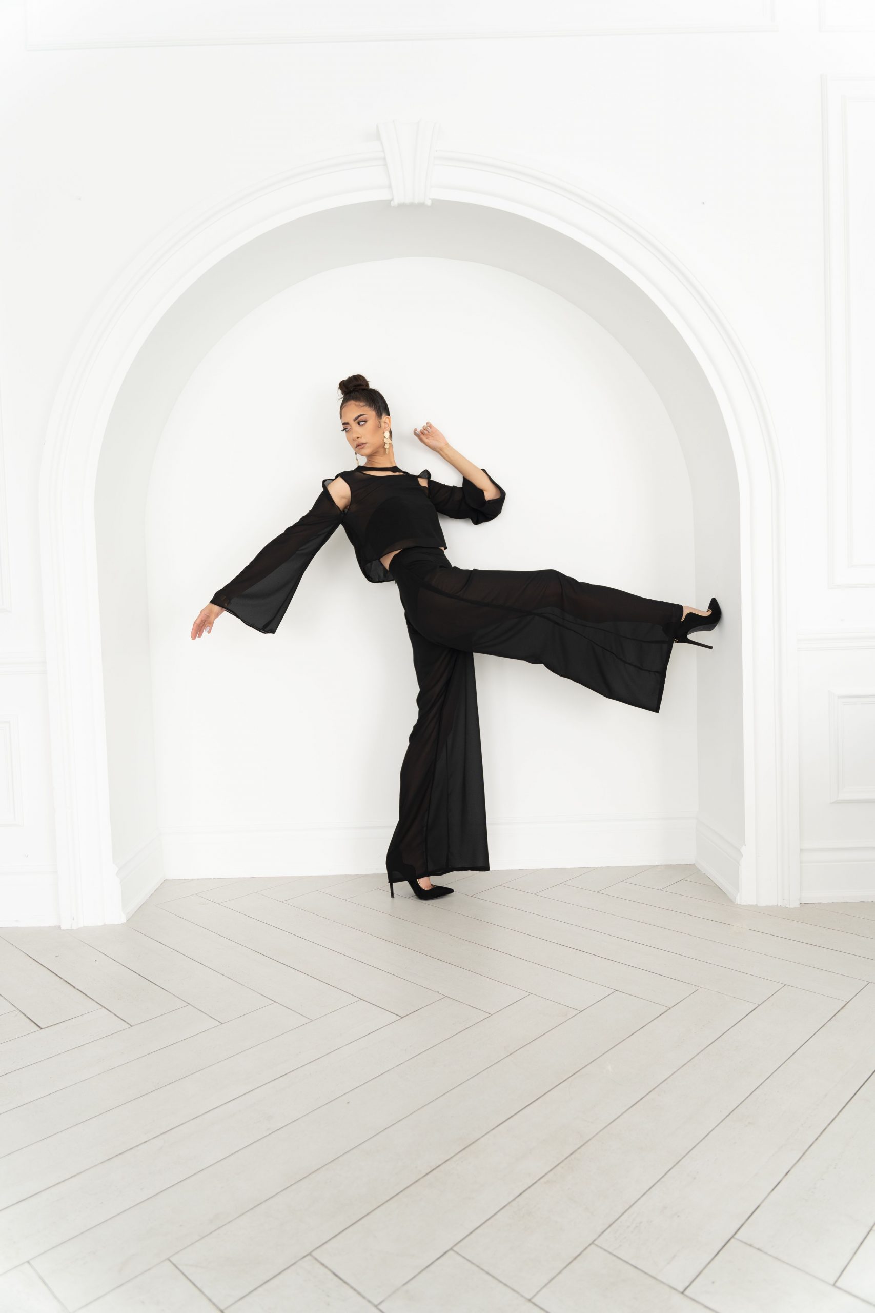 A woman in black outfit kicking around on white wall.