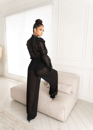 A woman in black outfit leaning on white couch.