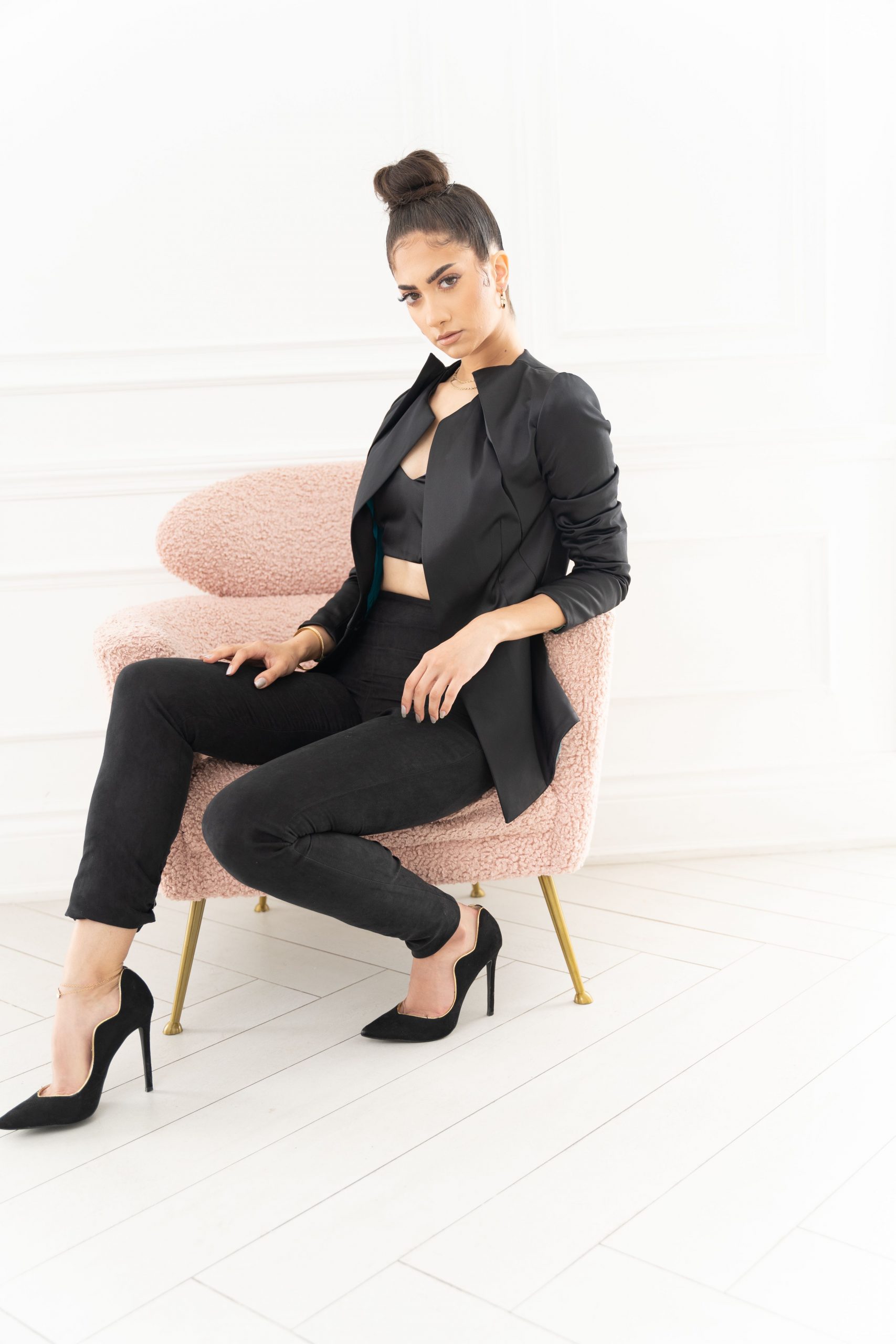 A woman in black outfit sitting on pink chair.