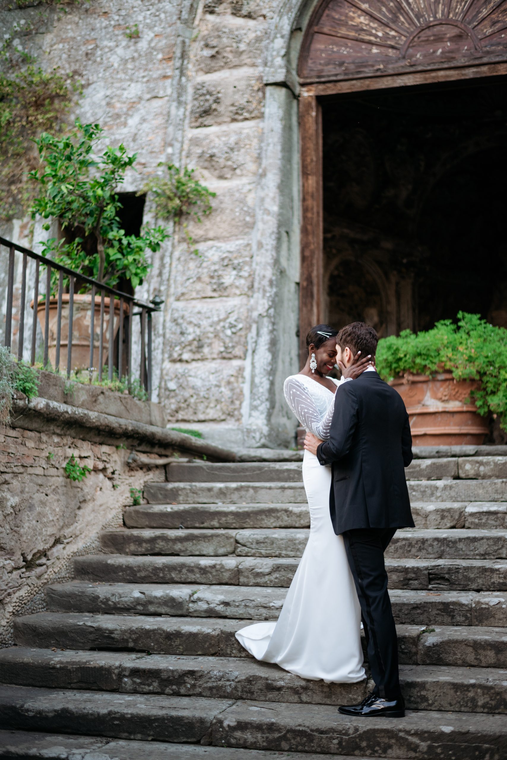 A bride and groom kissing on the steps of an old building.