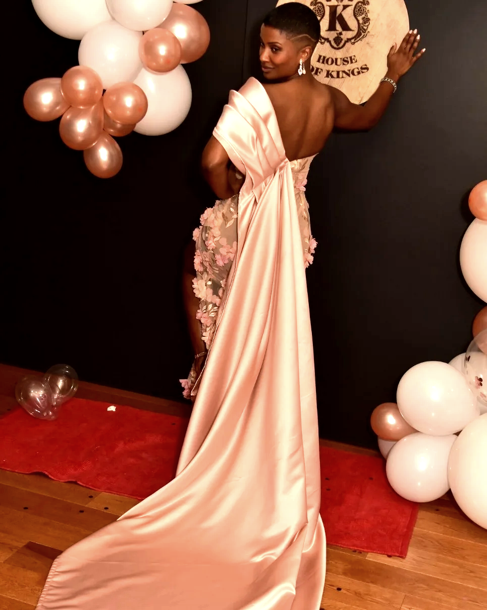 A woman in a long dress standing next to balloons.