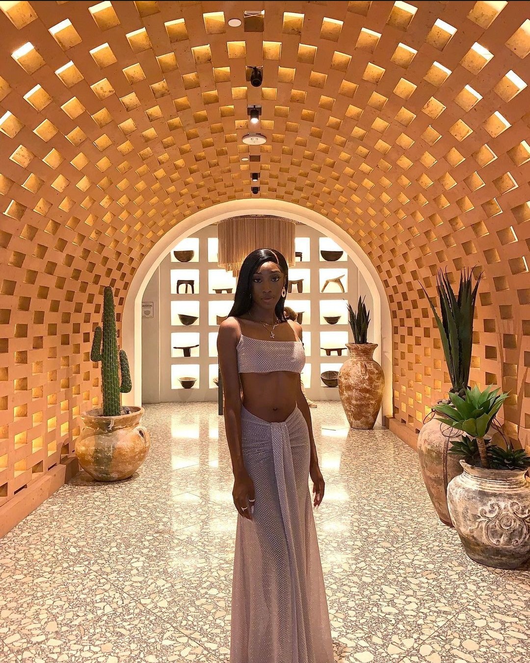 A woman in white dress standing inside of an indoor area.